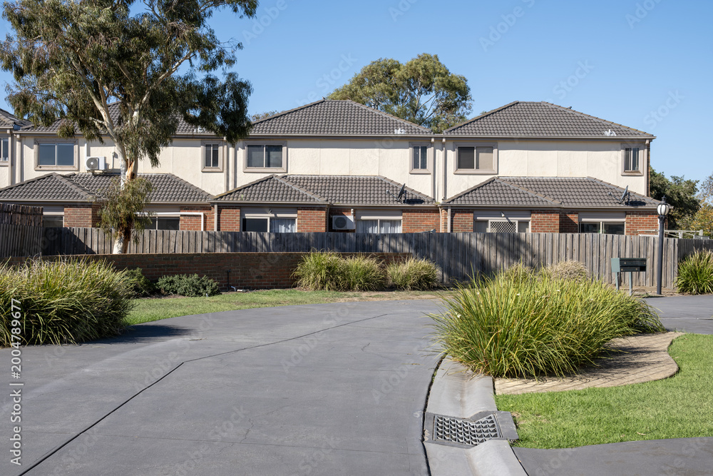 Fototapeta premium Modern townhouse complex in suburban Melbourne, Australia, featuring double-storey dwellings, native ornamental grasses and shared driveway. Median density housing, real estate and residential homes.