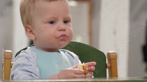 A cute baby holds a piece of bread and chews and eats. This video exudes innocence and is perfect for food and child-related topics