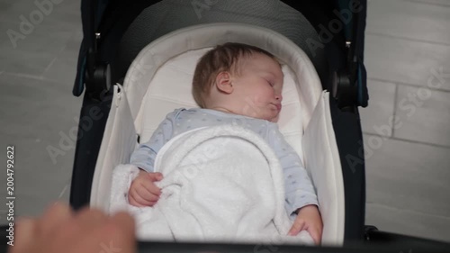 Child asleep beneath gentle illumination. Tot peacefully dozing under soft indoor light environment. Young child sleeping soundly in comfortable stroller beneath gentle indoor lighting ambiance