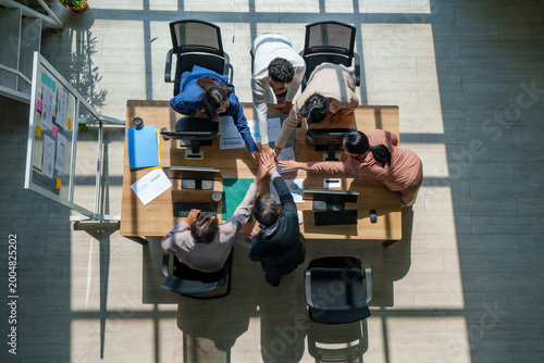Teamwork collaboration unity office meeting strategy business model marketing ai drive dynamic team with hands together over laptop on table, overhead view with motivated trust and growth