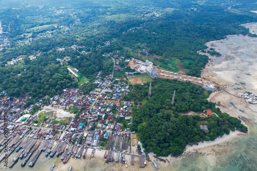 Tableau sur toile High-angle aerial view of a traditional fishing village in Tanjung Binga, Belitung, Indonesia, featuring coastal houses, fish drying platforms, and boats on turquoise water