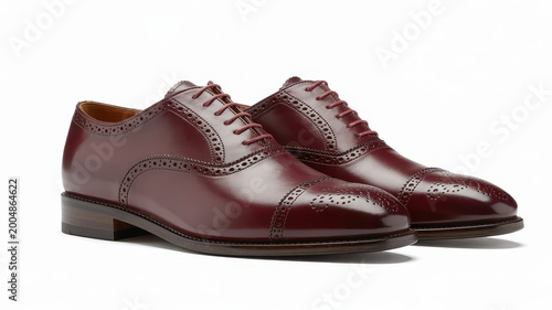 A pair of dark burgundy leather oxford shoes with brogue details, isolated on a white background