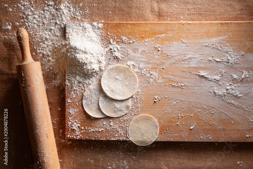 Fotografía Top View of Homemade Dumpling Dough Circles with Rolling Pin and Flour on Wooden