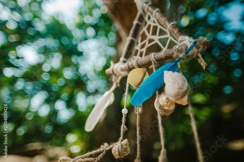 Rustic dreamcatcher with feathers and seashells in the forest