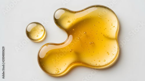Golden liquid splatter with droplets on white background shiny and smooth texture honey or oil spill