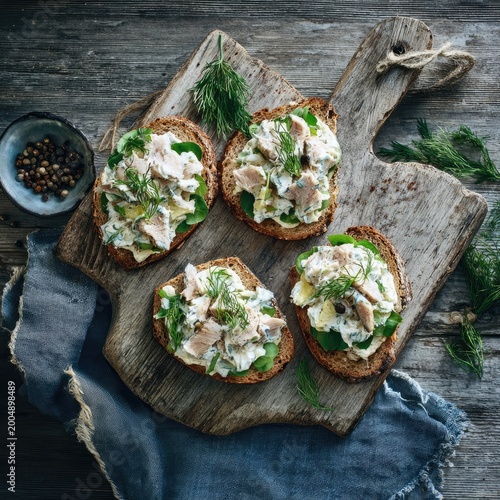 Salmon sandwiches on rustic wooden board with herbs and peppercorns
