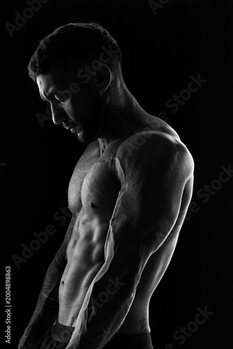 Gama, DF-Brasil – 04-29-2026: Athletic male torso with defined muscles and tattoos in dramatic black and white lighting