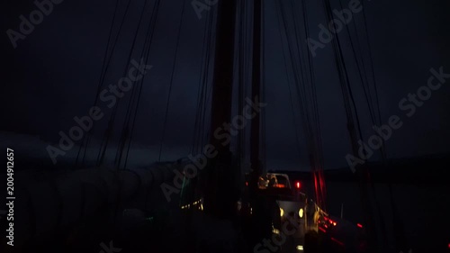 A vertical pan down from the topmast light of the two-masted schooner Amazone, revealing the intricate network of standing and running rigging against a deep night sky during an Antarctic expedition