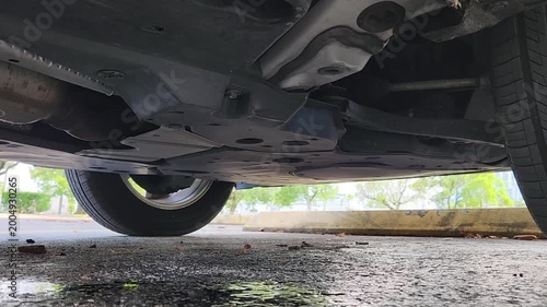 Water Dripping Under Car Undercarriage Forming Puddle on Asphalt