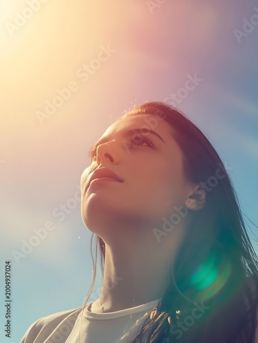 Young woman gazing upward in warm sunlight with dreamy rainbow lens flare