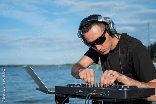 Caucasian man works as a DJ on the beach. 