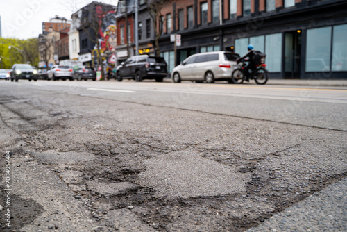 Фотография Close up of potholes on damaged asphalt road in urban street.