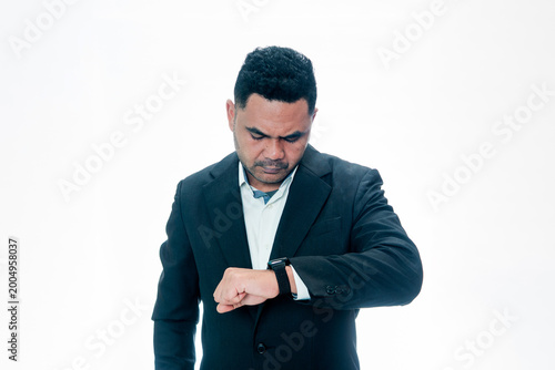 Quadro su tela A professional Indonesian man in a suit looking at his watch with a serious expression, suggesting lateness or deadline pressure, isolated on white