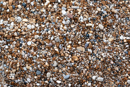 Fragment of a lake shore featuring small, multicolored pebbles and gravel, suitable for use as an abstract background or texture.