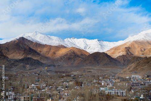 Winding mountain road curves through a vast snow-covered Himalayan landscape in Ladakh, India. High angle view of a dangerous silk route under winter conditions. Journey and extreme adventure concept.