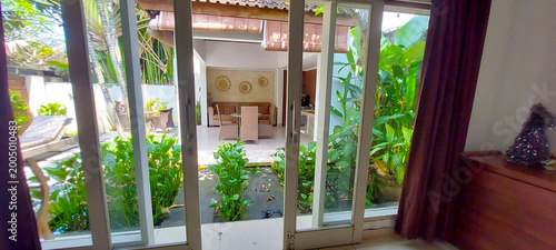 Foto View from inside a modern room looking out through sliding glass door to a sunli