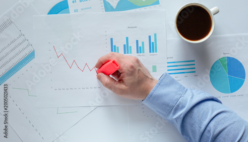 Close‑up of a male hand with red marker drawing a line on a financial chart. Symbol of growth, analysis, and business strategy.