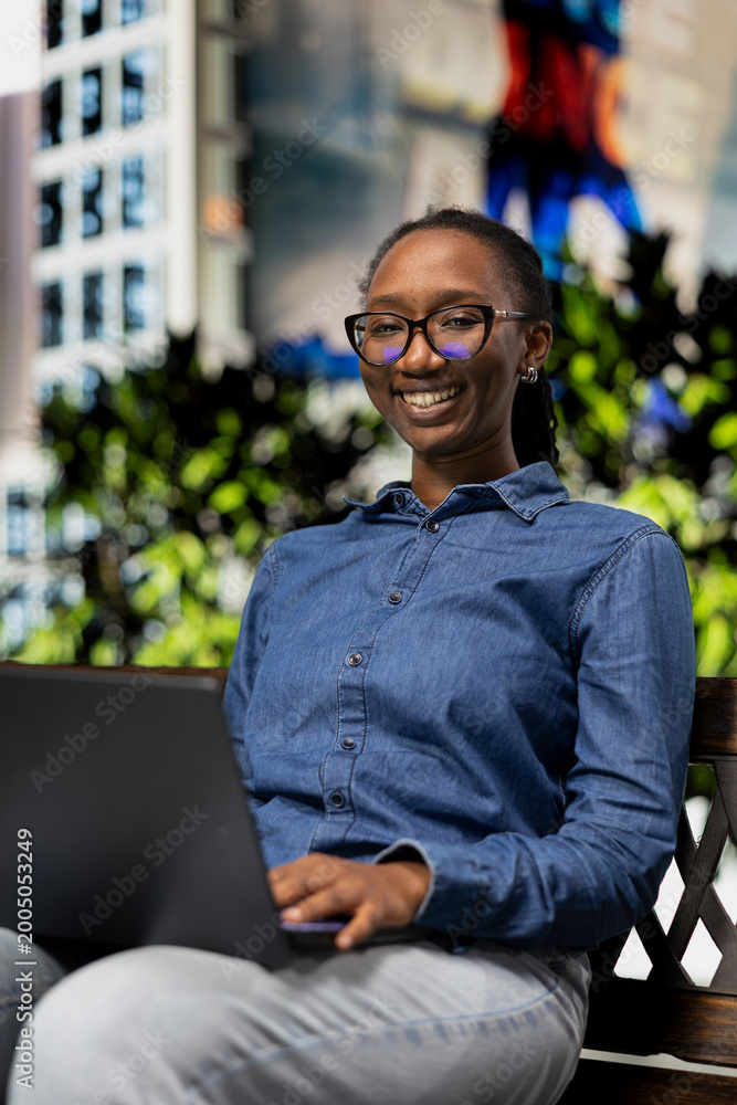 Obraz premium Sitting outside, laptop and portrait of smiling student doing homework, studying course materials. Reading articles online, notebook and cheerful woman on park bench preparing school assignment