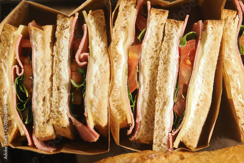 Obraz na plátně Fresh sandwiches stacked in paper holders at a deli