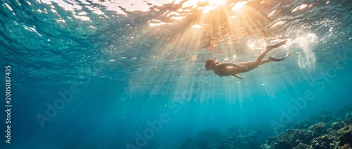 Person Freediving in Crystal Clear Blue Ocean with Sunlight Rays