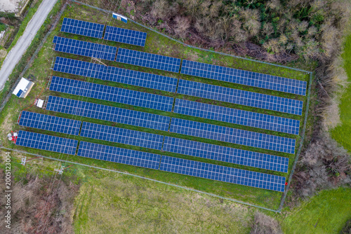 Aerial top down view of a rectangular photovoltaic solar farm producing renewable green energy surrounded by forest and grass in rural Corfu Greece