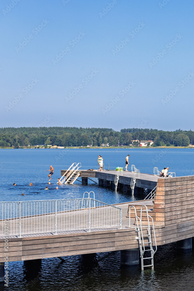 Fototapeta premium Wooden jetty in a lake with bathing people a sunny summer day