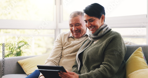 Foto Smile, tablet and senior couple on sofa in home with watching film show or series together
