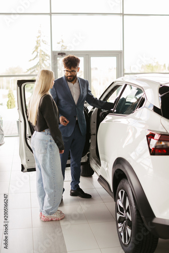 Salesman presenting new car to young customer