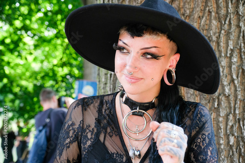 Portrait of a gothic woman with piercings, stretched ears, bold makeup on the annual Wave Gotik Treffen (Wave Gothic Meeting) in Leipzig, victorian picnic, Clara-Zetkin-Park