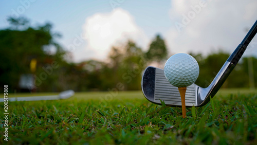 Golf clubs and balls on a green lawn in a beautiful golf course with morning sunshine.