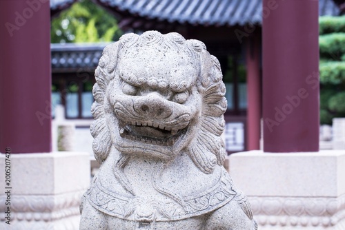 Canvastavla Stone lion statue stands guard at a traditional Chinese garden in bright dayligh