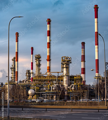 Industrial oil refinery plant with tall red and white chimneys.