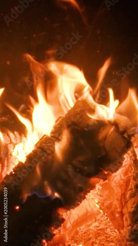 A home fireplace with a bright orange flame and logs burns and warms the room. Comfort and warmth in the cold winter atmosphere.