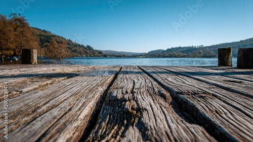 Wooden dock extends into a serene lake with trees and hills in background