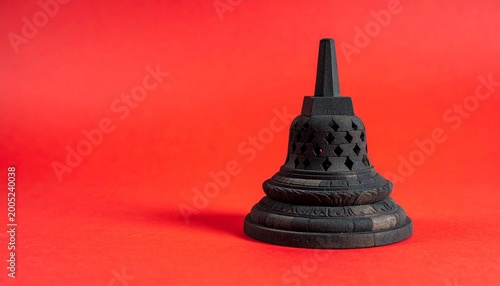 Miniature replica of a Borobudur stupa temple on a bright red background with copy space