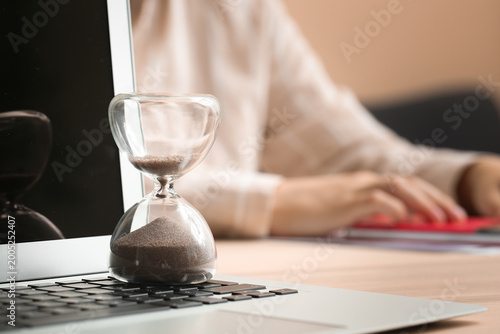 Hourglass with laptop near ...