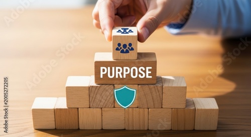 Hand placing teamwork block on purpose pyramid with security shield