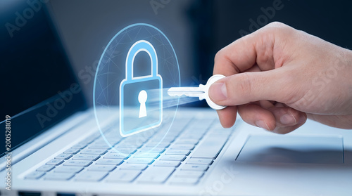 Hand holding key to secure laptop with glowing padlock icon for cybersecurity and data protection concept
