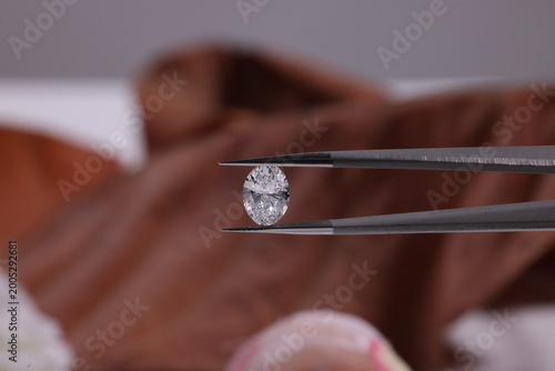 Tableau sur toile Close-up of an oval cut diamond held with precision tweezers against a dark background, showcasing clarity, brilliance, and luxury gemstone evaluation