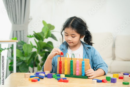 Young girl engaged in educational play with colorful wooden counting blocks and an abacus, enhancing cognitive skills and motor skills in bright indoor setting