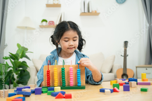 Young girl playing with colorful counting beads and blocks, focused on learning and developing fine motor skills in bright, cheerful home environment