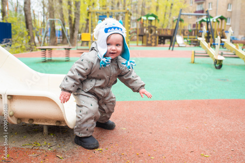 Happy baby boy just finished sliding down a slide on playground