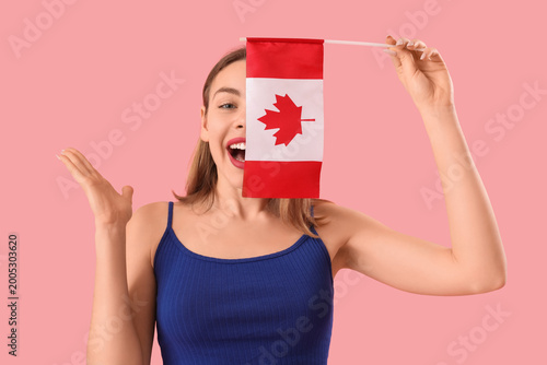 Happy young woman with flag of Canada on pink background
