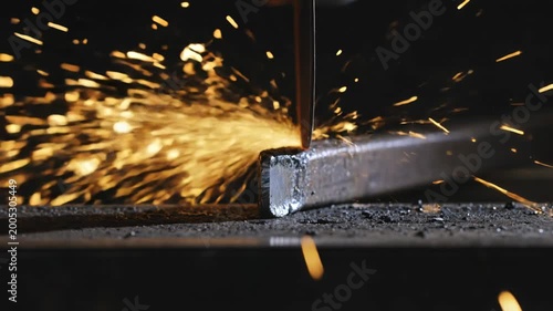 Fiery cascade of incandescent sparks erupts from powerful metal cutting in a deep night workshop