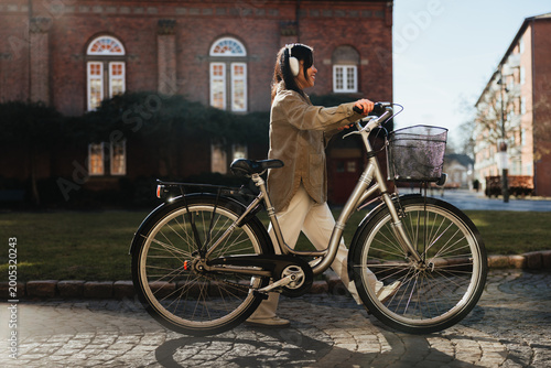 Woman walking bicycle through sunny urban courtyard