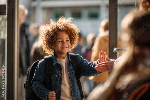 Young school child with backpack giving high five to parent outdoors. Concept of support, parenting, motivation, education and back to school routine.