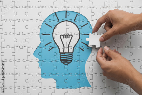 Hand holding a glowing light bulb with idea concept on blue puzzle background