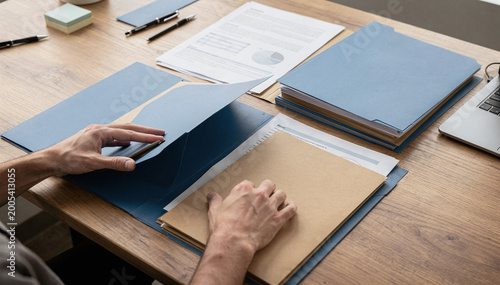 Organized workspace with hands opening a blue folder and documents spread