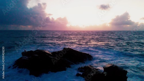 Static drone shot of waves crashing on rocks with sunset over the sea in Istanbul