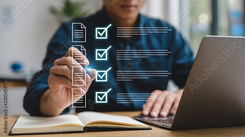 Man utilizing checklist and laptop for task management and completing assignments in a digital environment